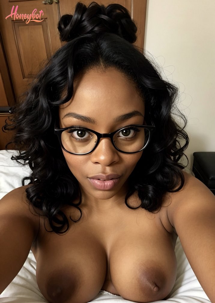 This image is a close-up of a person lying on a bed, with their upper body exposed. The person is wearing black glasses and has a topknot hairstyle. The individual's gaze is direc…